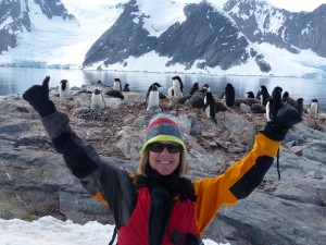 Marybeth in Antarctica with penguins, snowy mountains, and water—just the kind of moment travel expert Marybeth Bond would capture in a travel video.