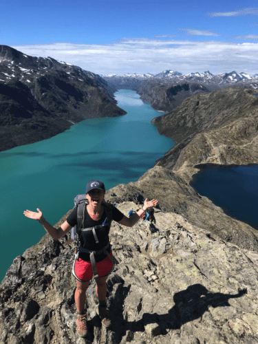 hiker on cliff above a deep blue fjord in Norway. Lotunheimen National Park