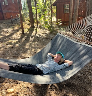 Gutsy Traveler: Unwind on a hammock in the peaceful woods, sunlight streaming through the trees and a rustic cabin nearby—experience true relaxation with High Country Access near Yosemite during off-peak times.