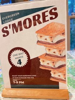Gutsy Traveler: Sign advertising Evergreen Lodge S'mores near Yosemite; one bag makes four s'mores. S'mores pictured with event time listed as 7–9 PM, perfect for roasting marshmallows at outdoor fire pits during off-peak hours.